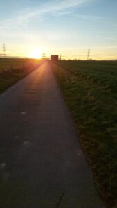 Eine Straße im Feld bei Sonnen untergang