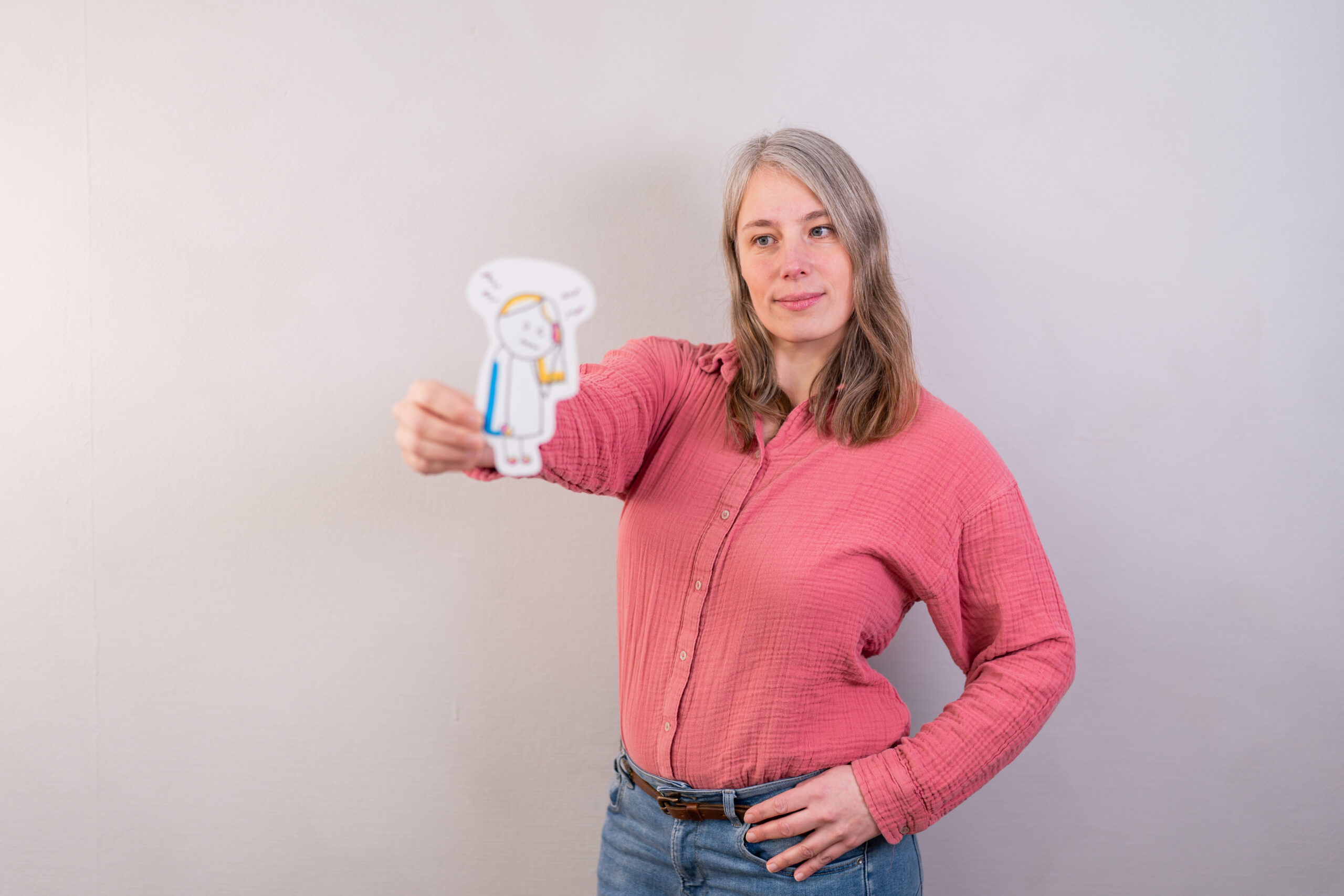 Sara schaut auf einen aus Papier ausgecshnittenen Sketchnote Figur mit Migräne und Kopfschmerzen